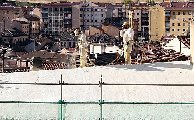 Operarios sin casco trabajan en las obras de un tejado en la capital segoviana. 