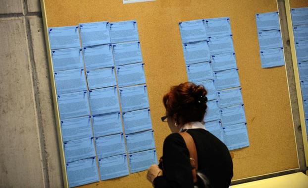 Una mujer revisa el tablón de ofertas de trabajo en una oficina de empleo.