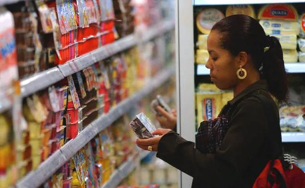 Una mujer observa un producto en un supermercado.