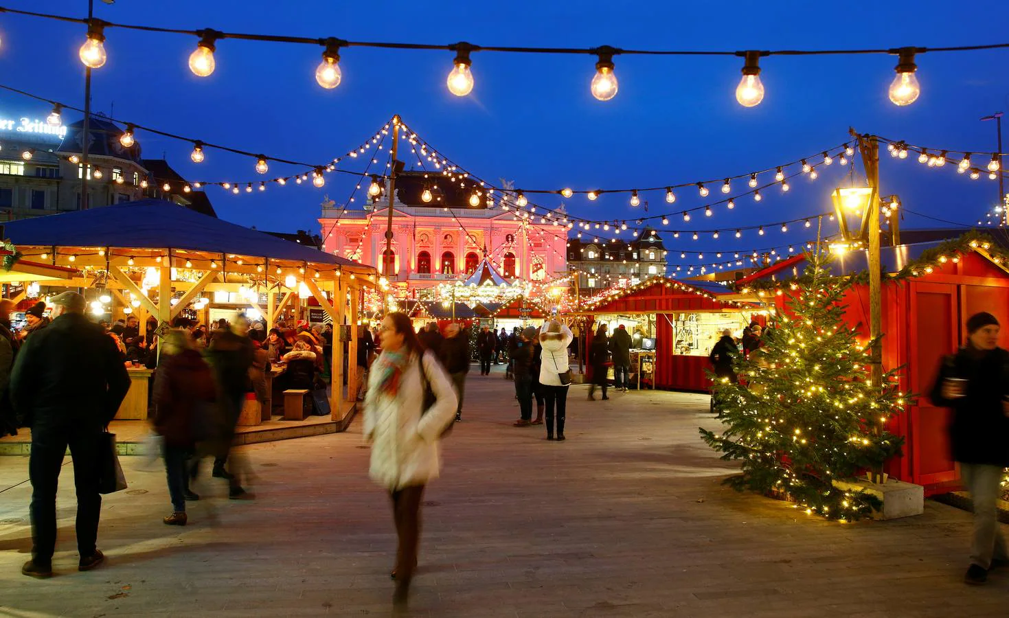 Una ópera iluminada se ve detrás de un mercado de Navidad en Zurich (Suiza).