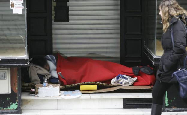 Una persona sin hogar, resguardado en el acceso de una tienda.