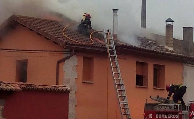 Los bomberos quitan las tejas para acceder al revestimiento en llamas.