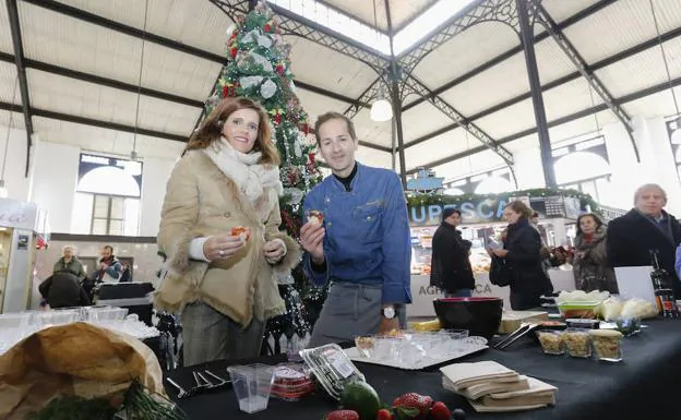 La concejala Almudena Parres y el bloguero David Monaguillo, en el Mercado Central con un postre de turrón y frutos rojos .