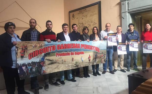 Organizadores y autoridades posan con una pancarta y los carteles del circuito.