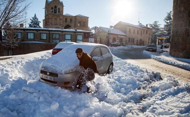 Un hombre con una pala intenta liberar su coche atrapado por la nieve en Ávila. 