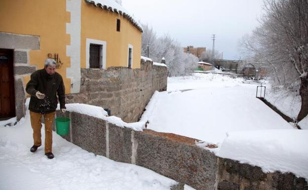 Un hombre esparce sal a la entrada de su establecimiento situado junto al río Adaja que ha amanecido congelado a su paso por Ávila. 