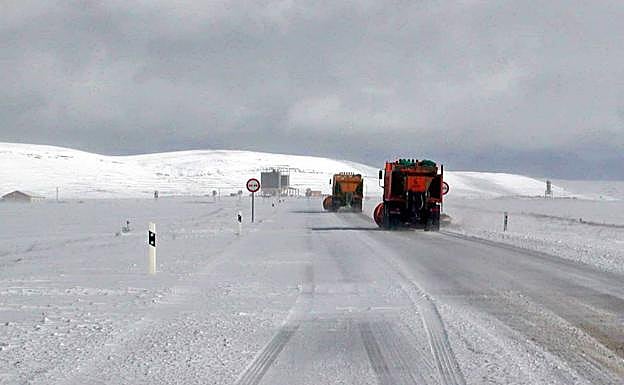 Dos máquinas limpian la nieve y esparcen sal sobre una carretera.