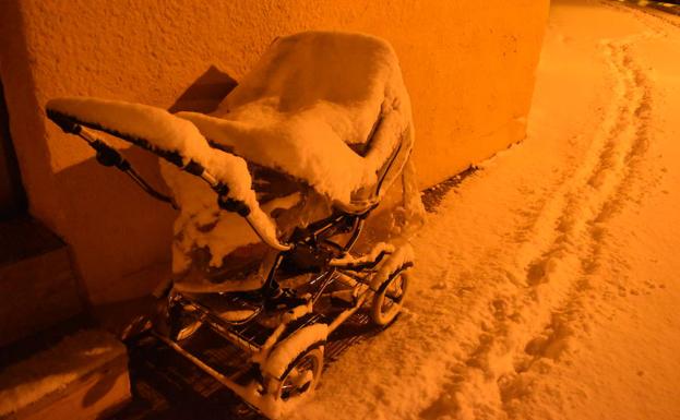 Un carrito de bebé cubierto de nieve de madrugada en Aguilar.