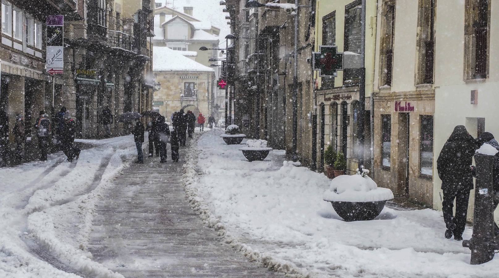 Niños y mayores caminando entre las calles por las zonas donde las máquinas han quitado la mayor capa de nieve