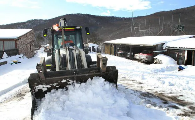 Una pala excavadora limpia de nieve un aparcamiento en Brañosera (Palencia).