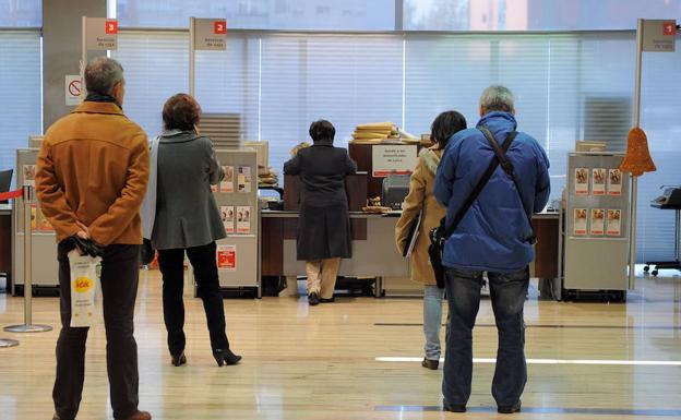 Varios clientes hacen cola para ser atendidos en una entidad bancaria.