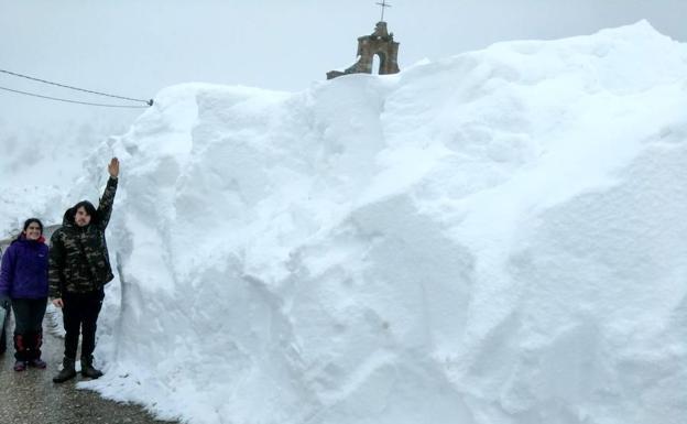 Un joven indica la altura de la nieve junto a la carretera en Piedrasluengas.