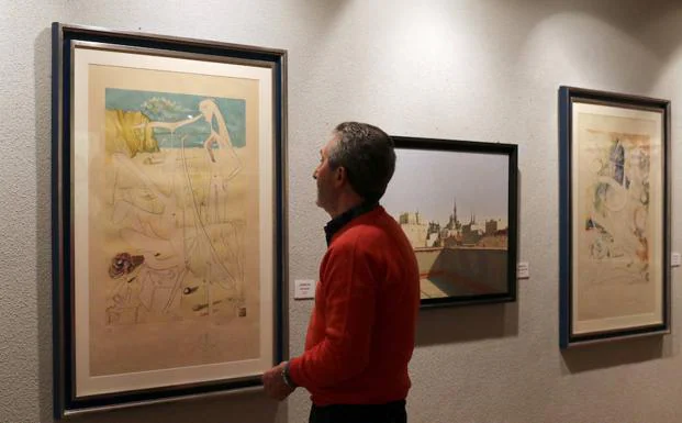 Un visitante observa uno de los cuadros de la exposición. 