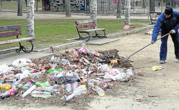 Un empleado de limpieza acumula las botellas dejadas por los asistentes al botellón.