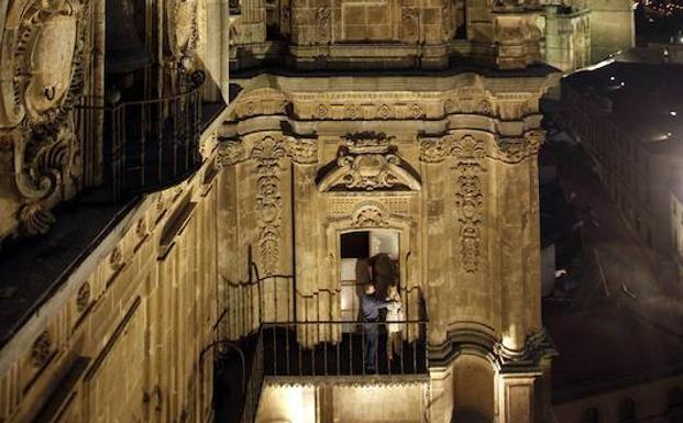 Dos personas observan la ciudad desdeun balcón de la torre de la Clerecía.