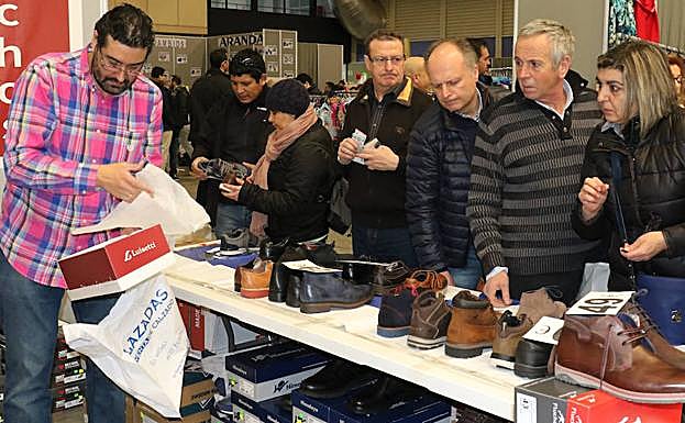 Varios visitantes observan los productos de calzado de uno de los expositores durante el fin de semana.
