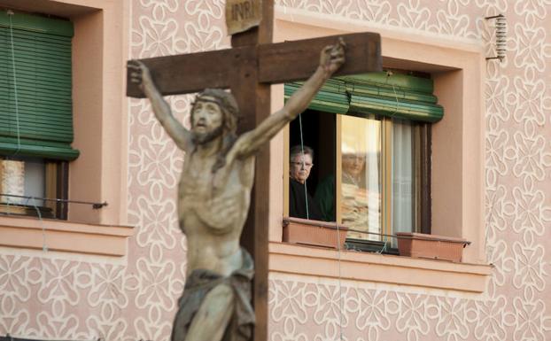 Unos vecinos observan el paso del Santísimo Cristo por su calle. 