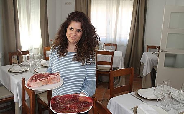 Amparo muestra con orgullo un plato de cecina y otro con un llamativo chuletón. 