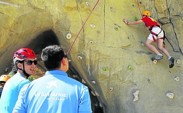 Un niño escala la cueva junto a dos voluntarios. 