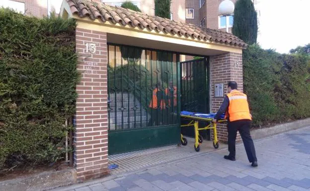 Los operarios del Servicio Forense trasladan el cuerpo de la fallecida del portal del número 15 de la calle Federico Landrove Moiño, junto al centro cívico de Parquesol.