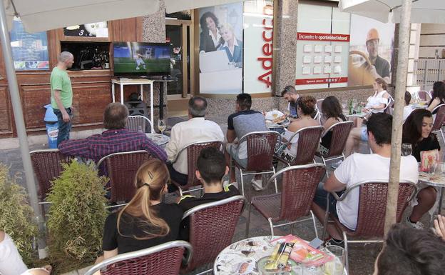 Varias personas siguen un partido de la selección española en una terraza en Palencia. 