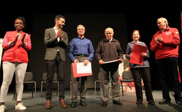 Representantes de Cruz Roja aplauden a tres socios de la entidad, que recibieron ayer un homenaje en el teatro Juan Bravo. 