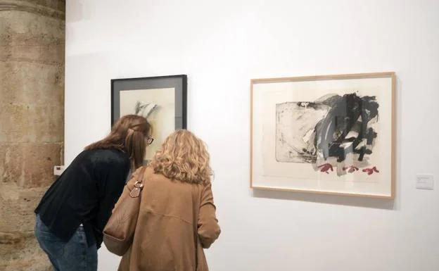 Dos personas observan las obras en la sala de exposiciones de Santo Domingo.
