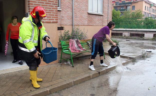 Un bombero y una vecina de Cuéllar achican agua tras la tromba que cayó el 14 de junio. 