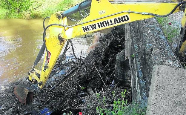 Una maquina desbroza el cauce de un río. 