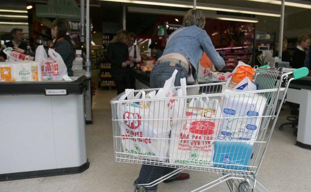 Una mujer llena el carro de la compra con bolsas en un supermercado de la ciudad. 