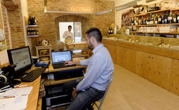 El propietario de un pequeño negocio consulta en su portátil la información de su catálogo en línea. 