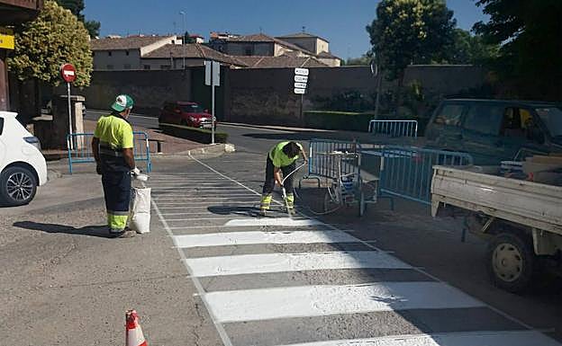 Operarios pintan un paso de cebra en una calle de Cuéllar. 