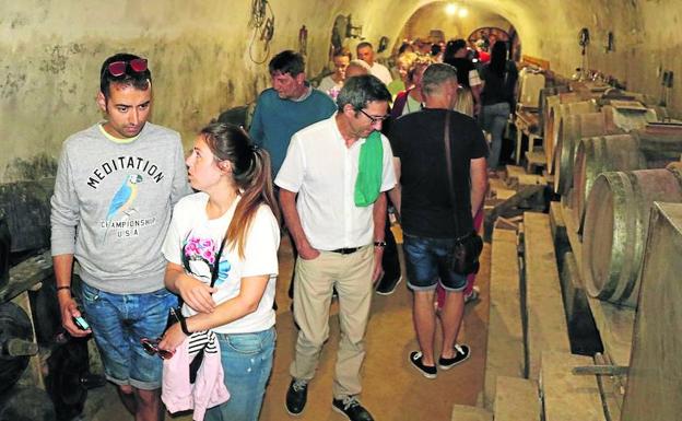 Los participantes en la visita guiada observan unas cubas.
