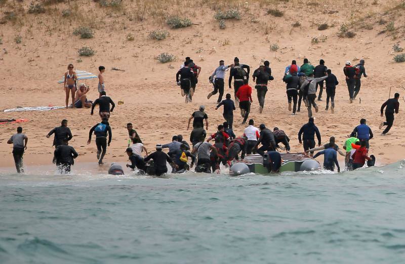 Los inmigrantes desembarcaron en una pequeña lancha ante la mirada de los bañistas.