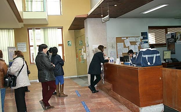 Varias personas, ante el mostrador del centro de salud. 