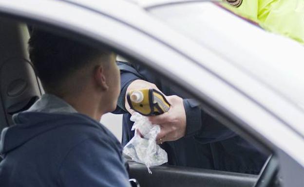 Un policía realiza una prueba de alcoholemia al conductor de un turismo.