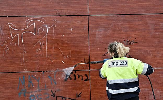 Una trabajadora del Servicio de Limpieza elimina una pintada.