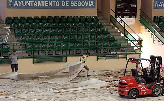 Dos operarios proceden a la retirada del parqué del Pedro Delgado.