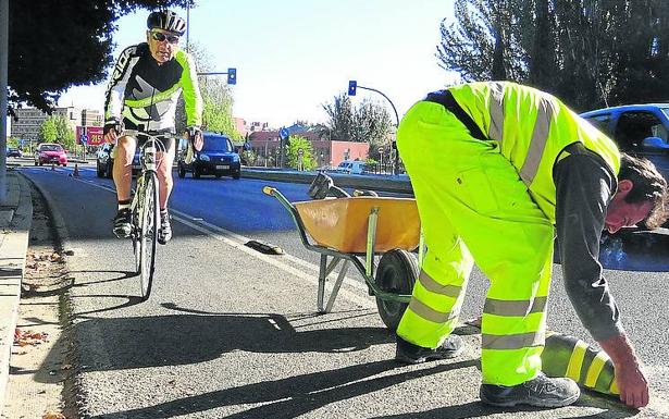 Un operario coloca el nuevo separador al paso de un ciclista, 