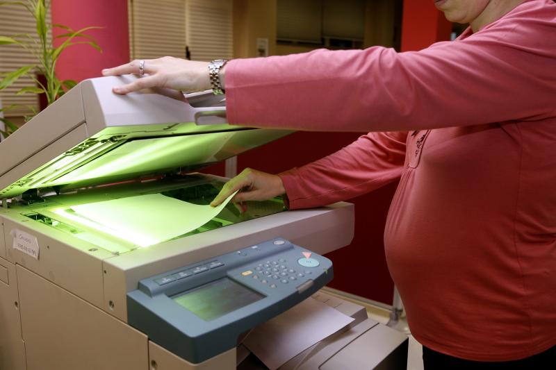 Una mujer embarazada hace fotocopias en su centro de trabajo.