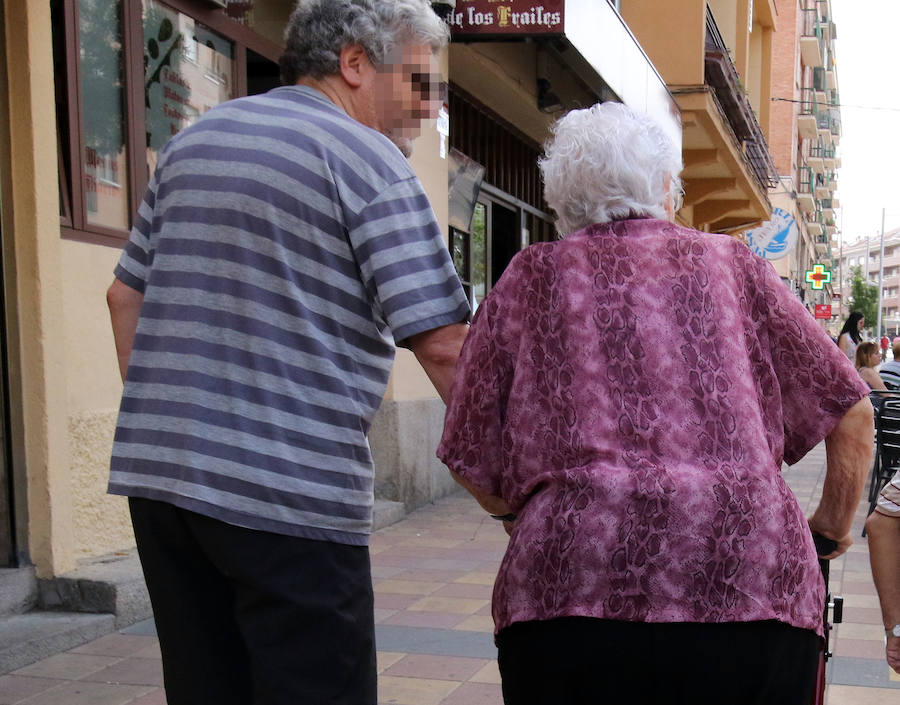 Un hombre acompaña a una señora mayor por la calle José Zorrilla.