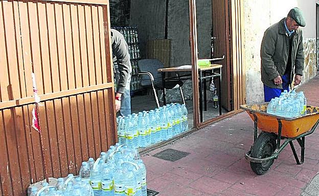Un vecino de la localidad carga agua embotellada en una carretilla. 