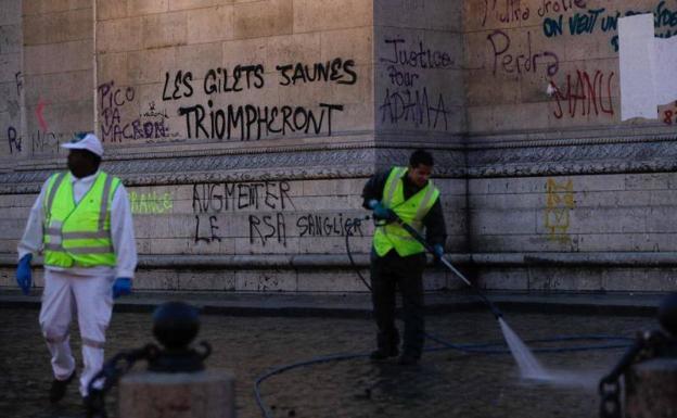 Operarios limpian las pintadas realizadas en los muros del Arco del Triunfo durante las protestas.
