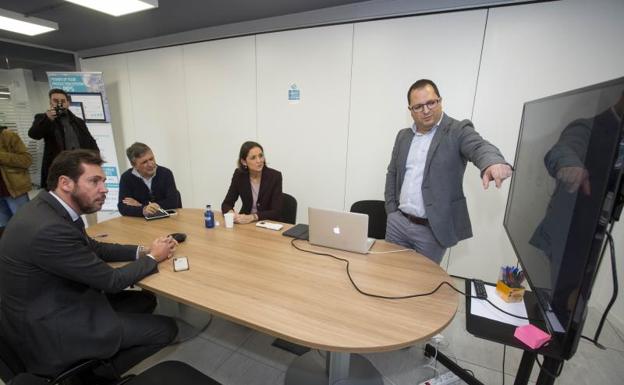 Roberto Delgado, consejero delegado de Mobile Lean, explica a la ministria Reyes Maroto y al alcalde Óscar Puente la aplicación que desarrolla su compañía. 