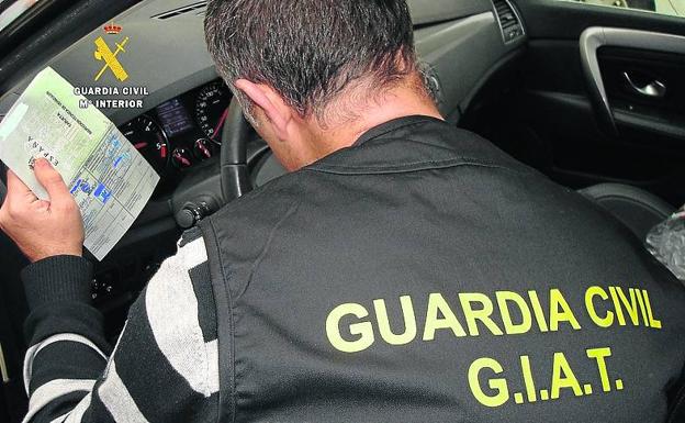 Un guardia civil del GIAT comprueba las tarjetas de inspección técnica de los vehículos. 