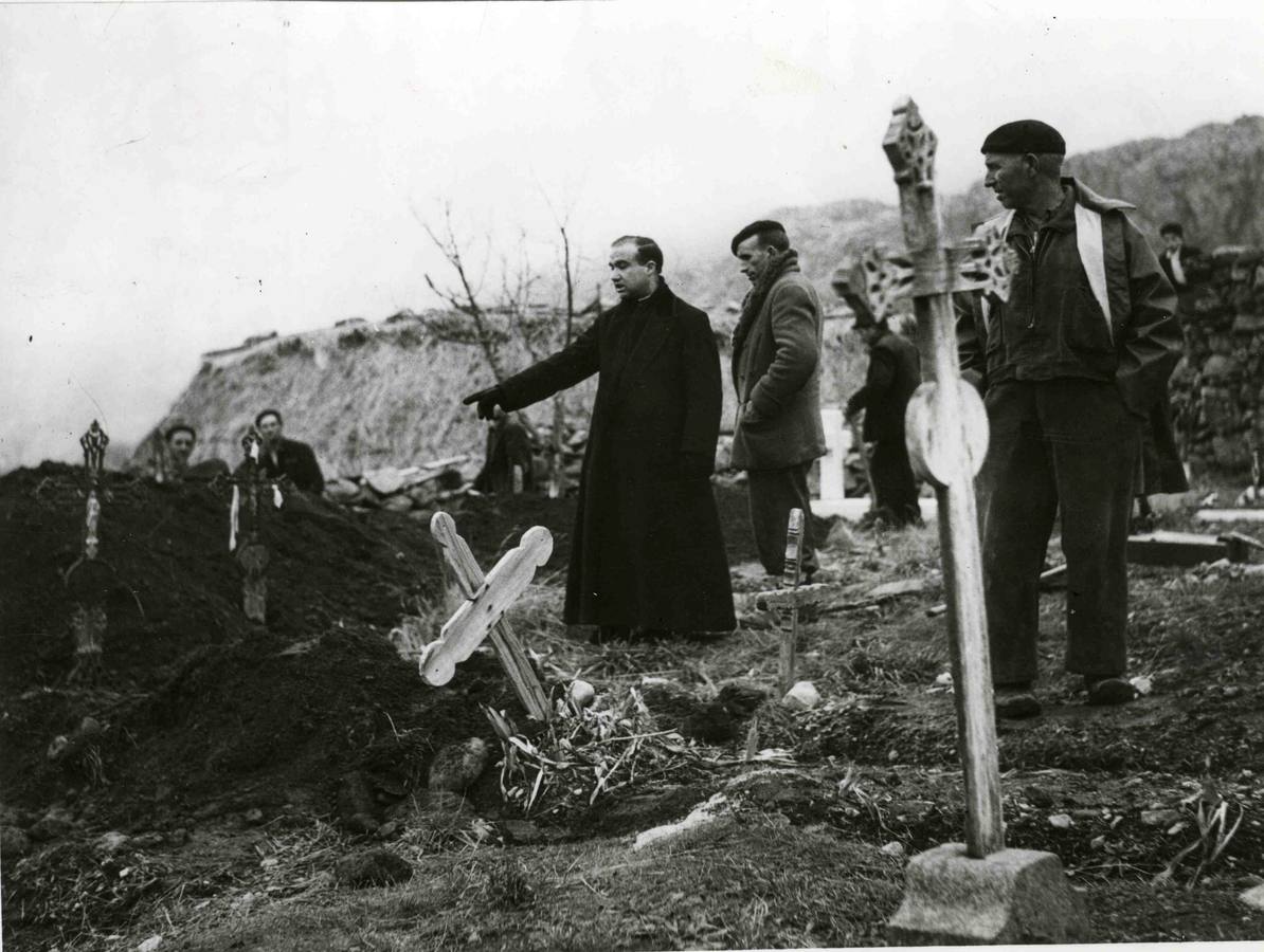 Un sacerdote señala la tumba de uno de los pocos desaparecidos cuyo cadáver fue rescatado del agua.