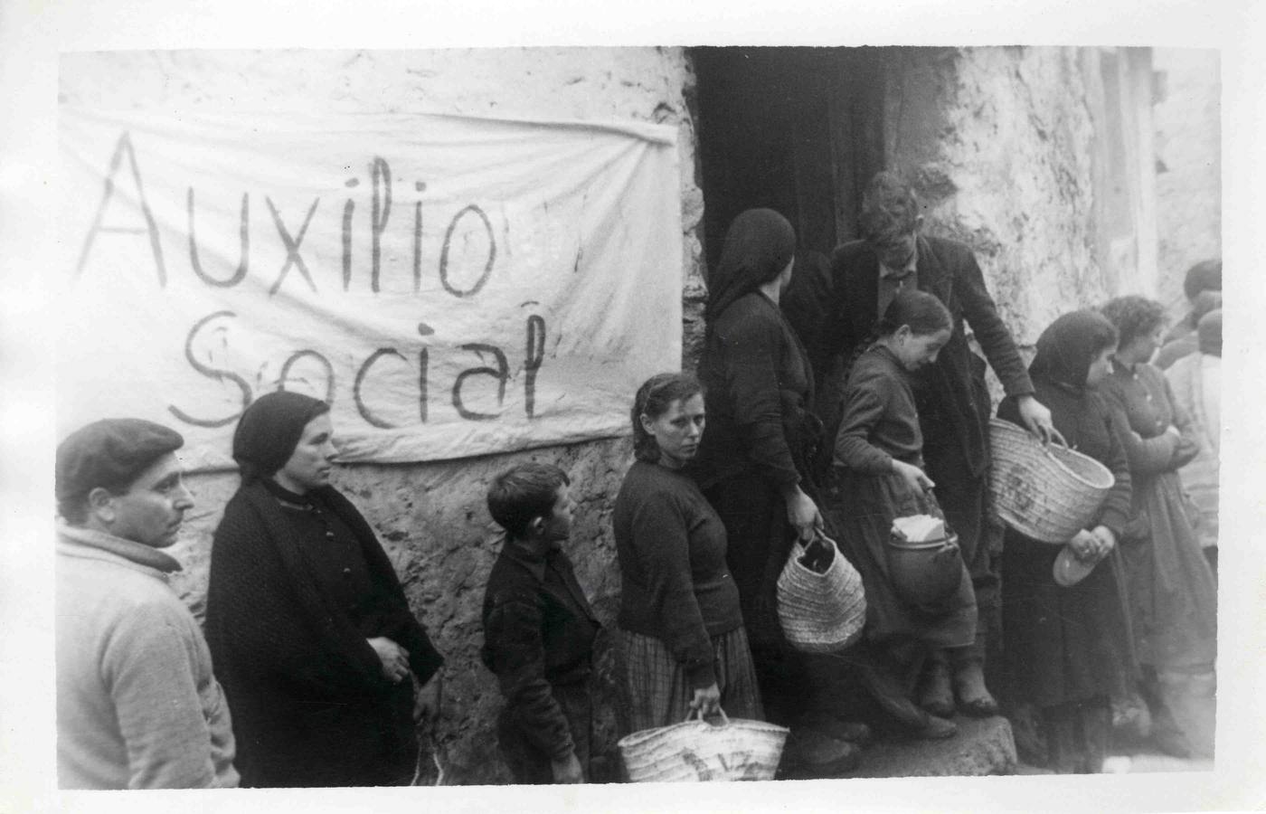 Supervivientes de la catástrofe hacen cola ante Auxilio Social para recibir alimentos.