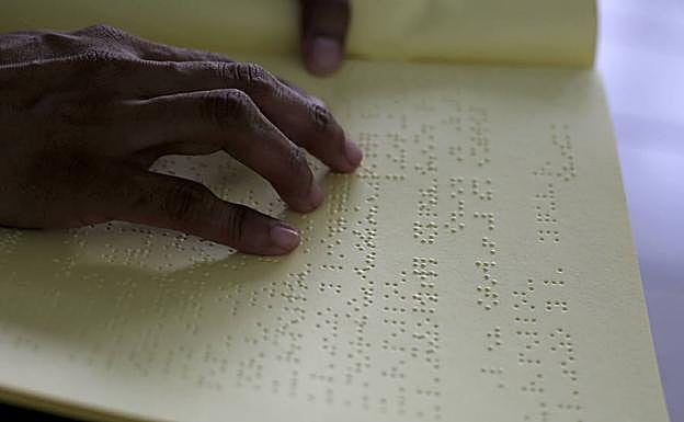 Una persona invidente lee un libro en braile. 