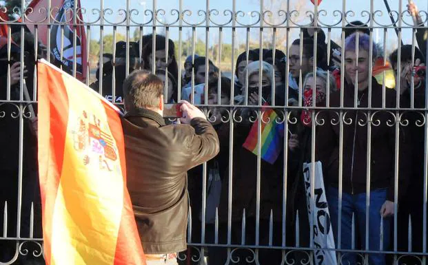 Uno de los asistentes al acto de Vox porta una bandera de España mientras hace fotos a los manifestantes. 