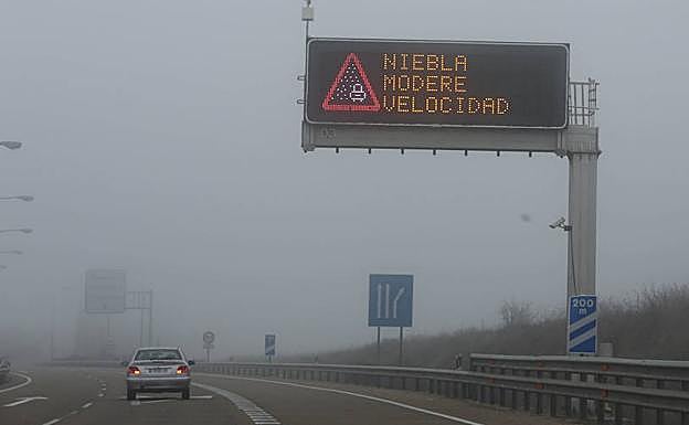 Un coche circula por la Autovia A-62 con aviso de niebla.